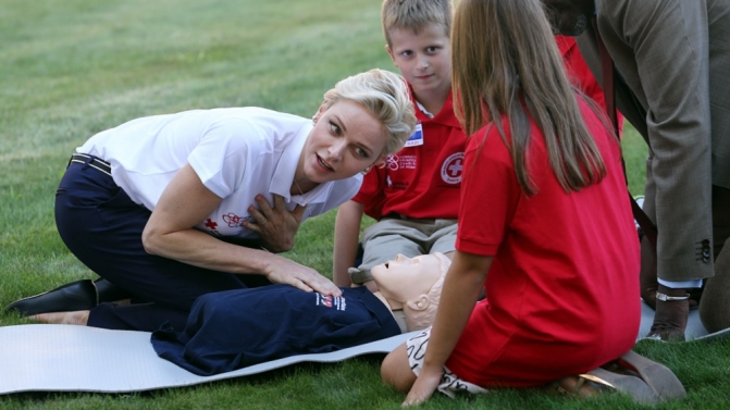 Monaco’s Princess Charlene, goodwill ambassador for the IFRC for first aid, demonstrates on a dummy how to practice first aid to chidren at the UN in Geneva
