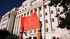 "Sai do meu útero". Este foi um dos cartazes levados ao senado do Alabama para protestar contra as medidas restritivas em torno do aborto, aprovadas esta semana [Fotografia: Christopher Aluka Berry/Reuters]