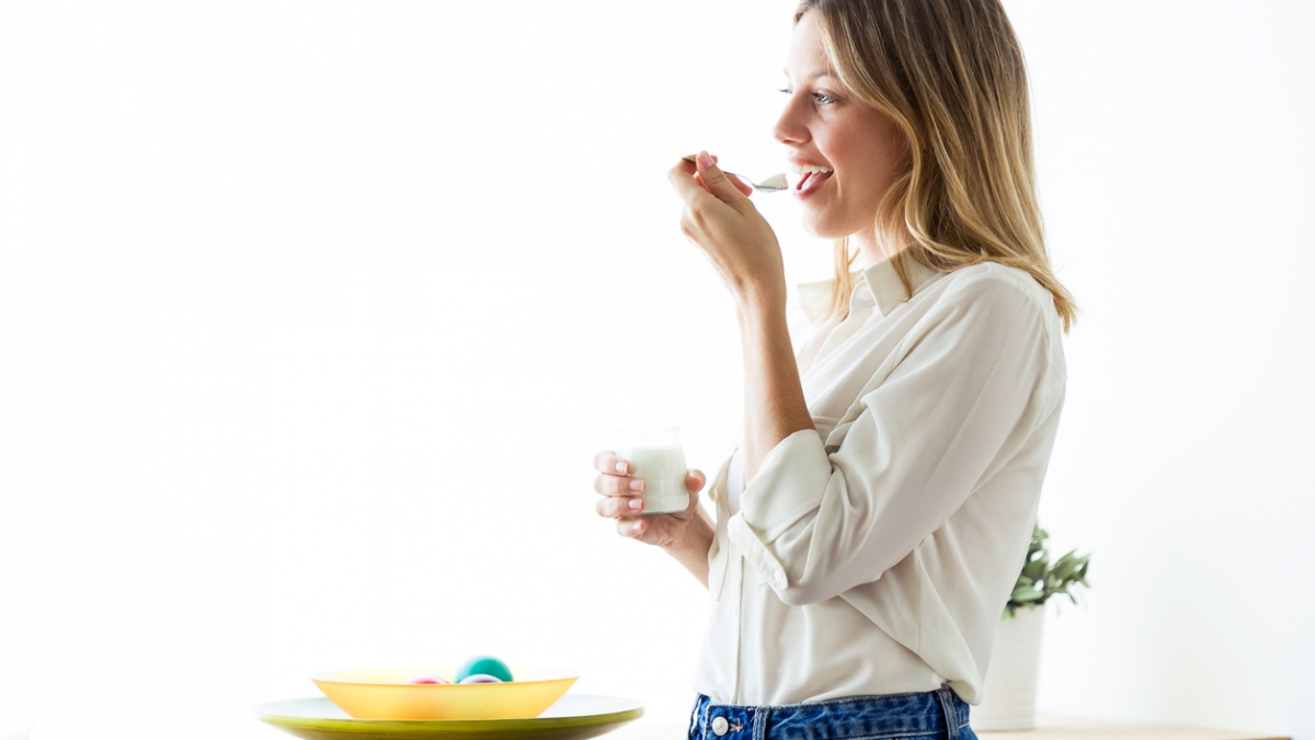 Beautiful young woman eating yogurt at home.