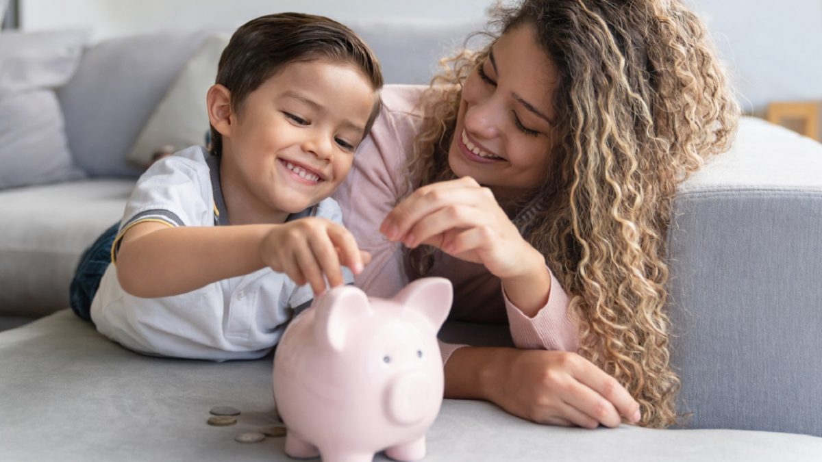 Happy mother and son saving money in a piggybank