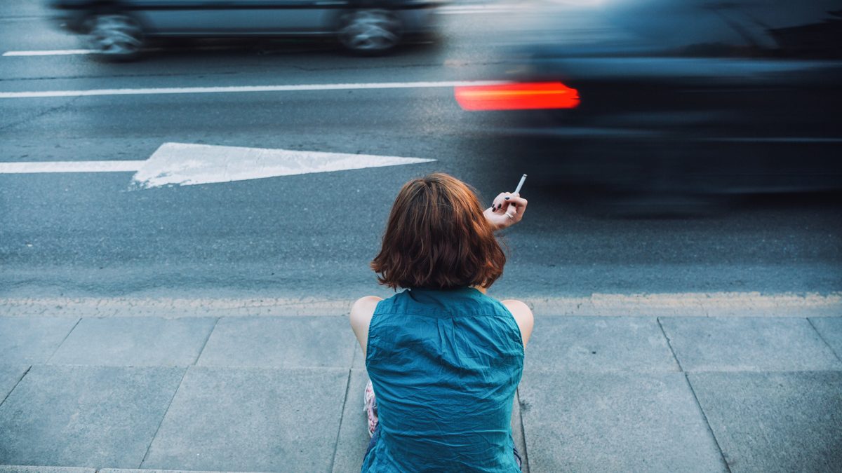Teenager smoking on a sidewalk
