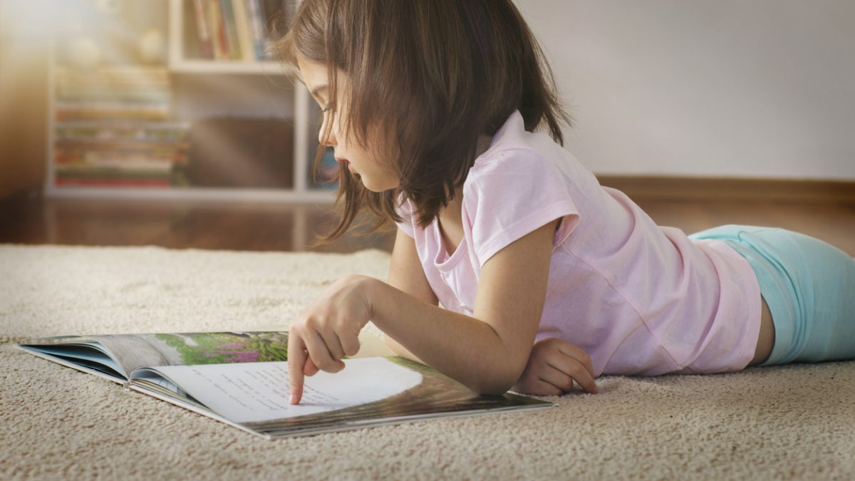 Cute girl reading a book on the floor