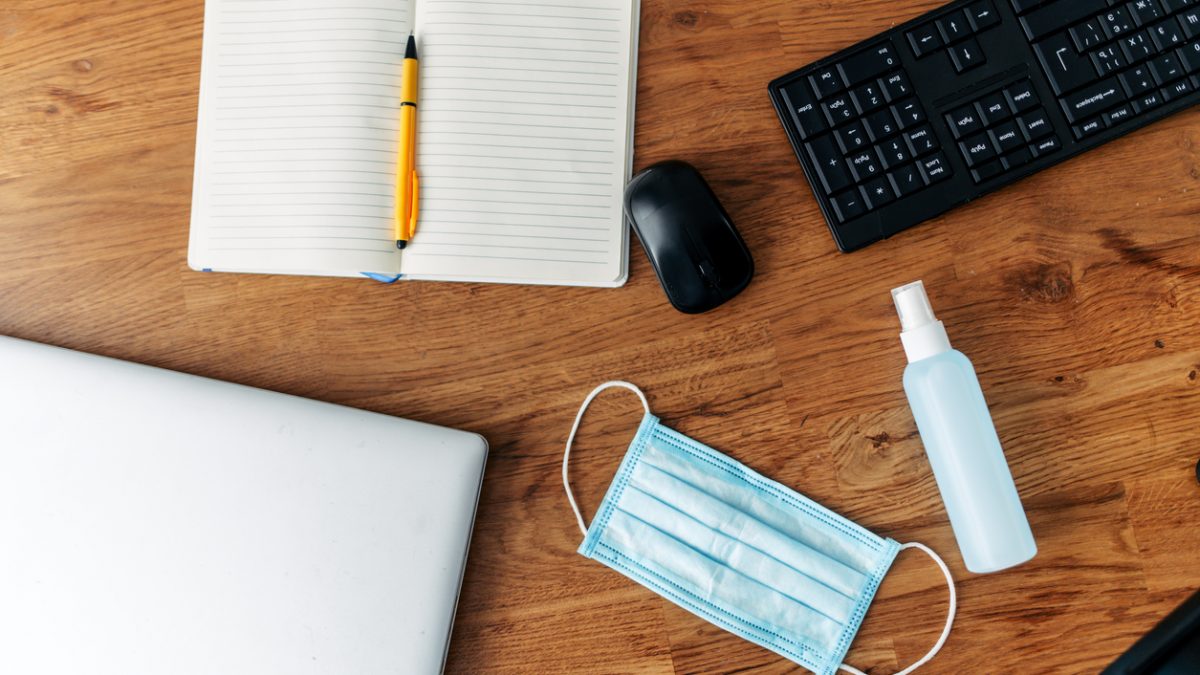 Mask and sanitizer on the desktop, near keyboard