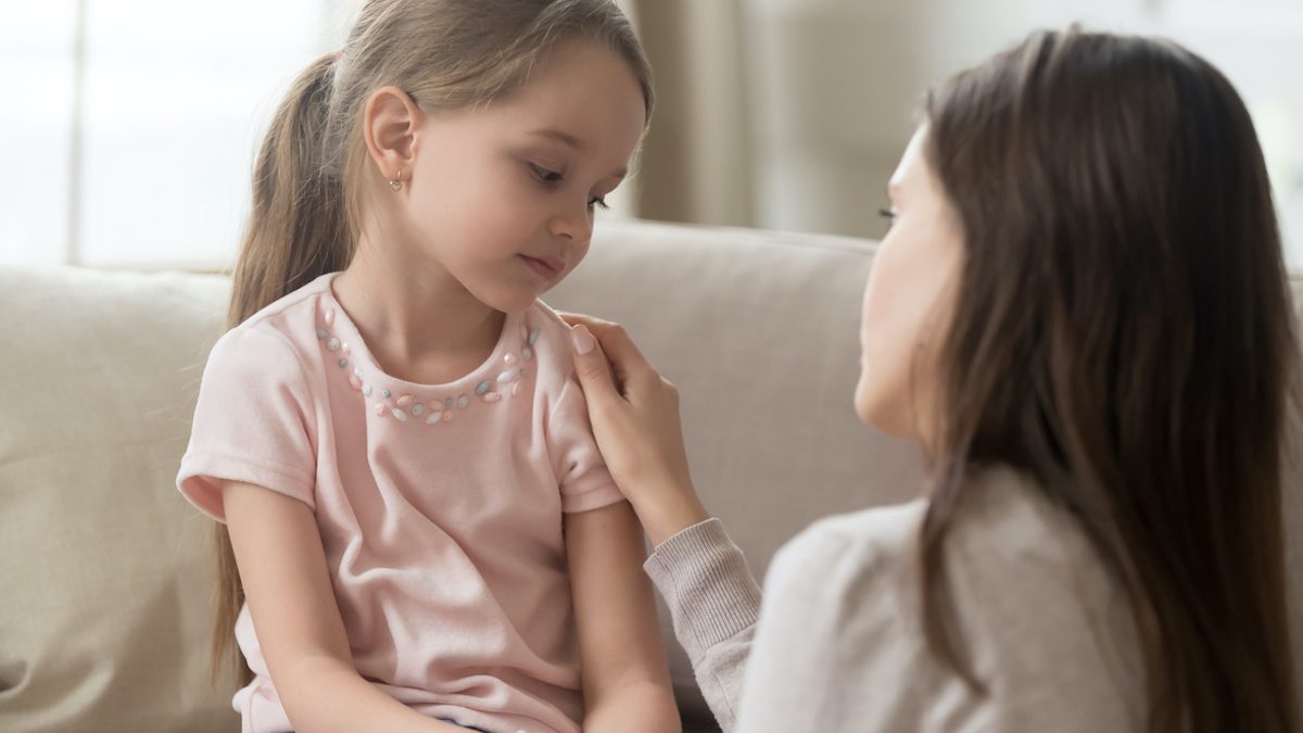 Loving mom talking to upset little child girl giving support