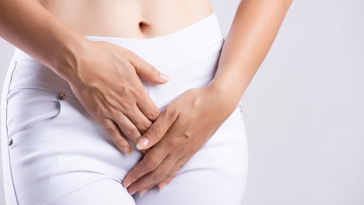 Young woman having painful stomachache with hands holding pressing her crotch lower abdomen. Medical or gynecological problems, healthcare concept Young woman having painful stomachache with hands holding pressing her crotch lower abdomen. Medical or gynecological problems, healthcare concept