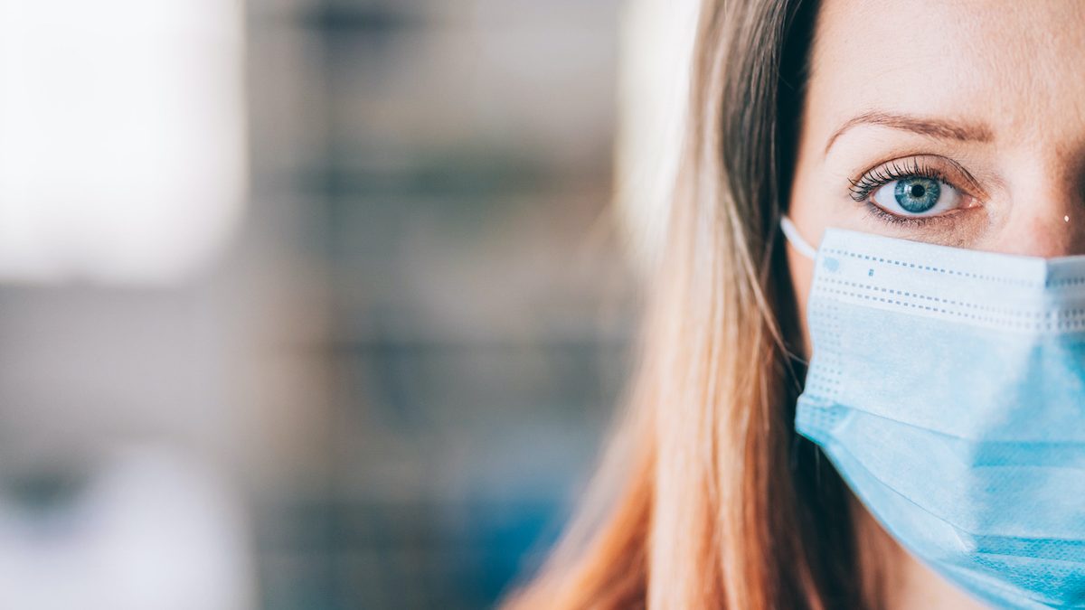 Woman wearing protective face mask in the office for safety and protection during COVID-19