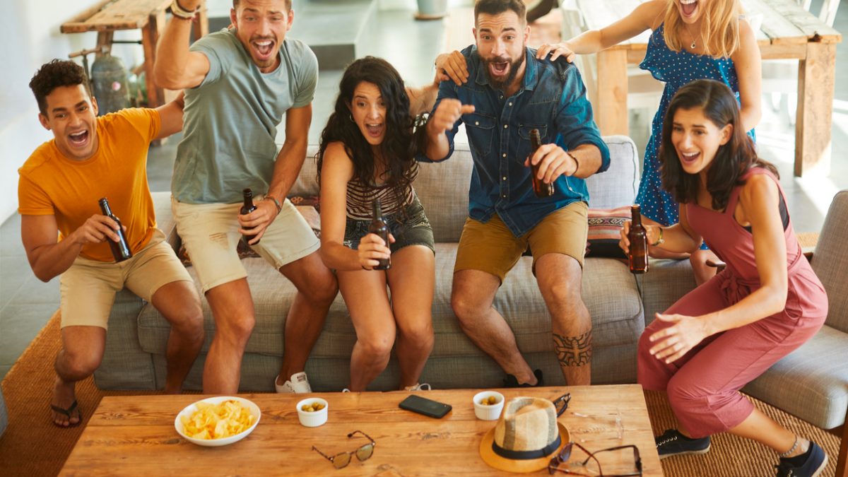 Group of friends jump in joy when their team scores a goal.