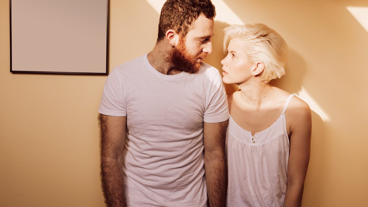 Portrait of young couple in living room looking each other.