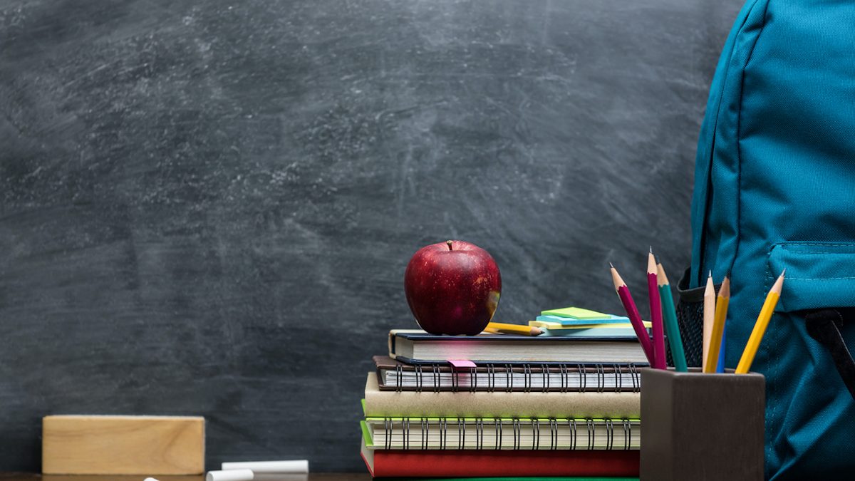 Stack of books, stationery and education supplies on wooden desk