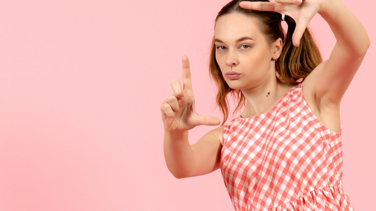 front view young attractive girl in cute pink dress smiling and taking picture with her hands on a pink background girl model youth color emotions pink