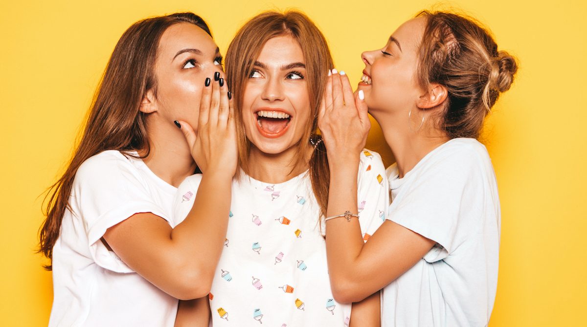 Three young beautiful smiling hipster girls in trendy summer clothes. Sexy carefree women posing near yellow wall in studio. Positive models going crazy and having fun.Share secrets, gossip