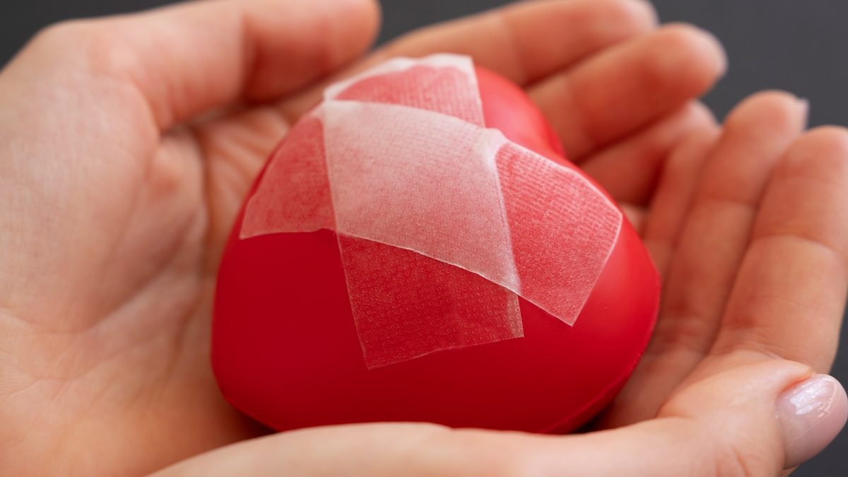close-up-person-holding-broken-heart-put-back-together-with-scotch-tape close-up-person-holding-broken-heart-put-back-together-with-scotch-tape